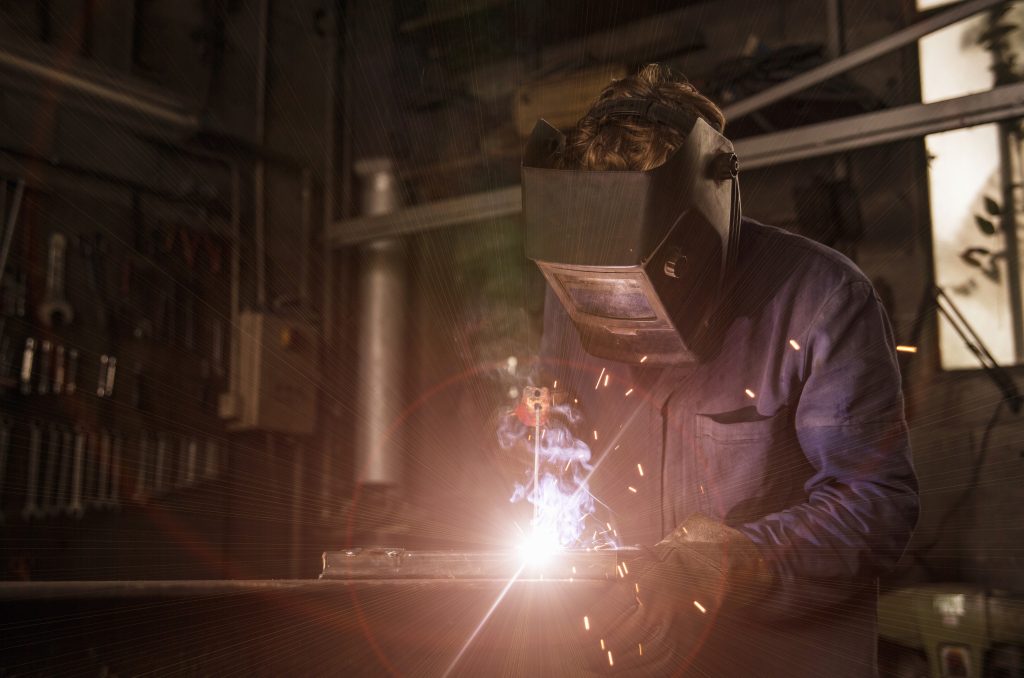 Welder at work with sparks flying in a dim workshop.