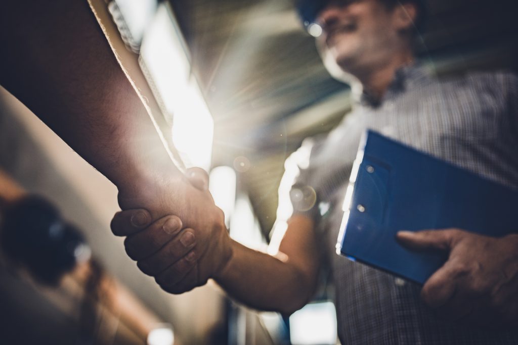 Close up of inspector shaking hands with unrecognizable person in a factory.
